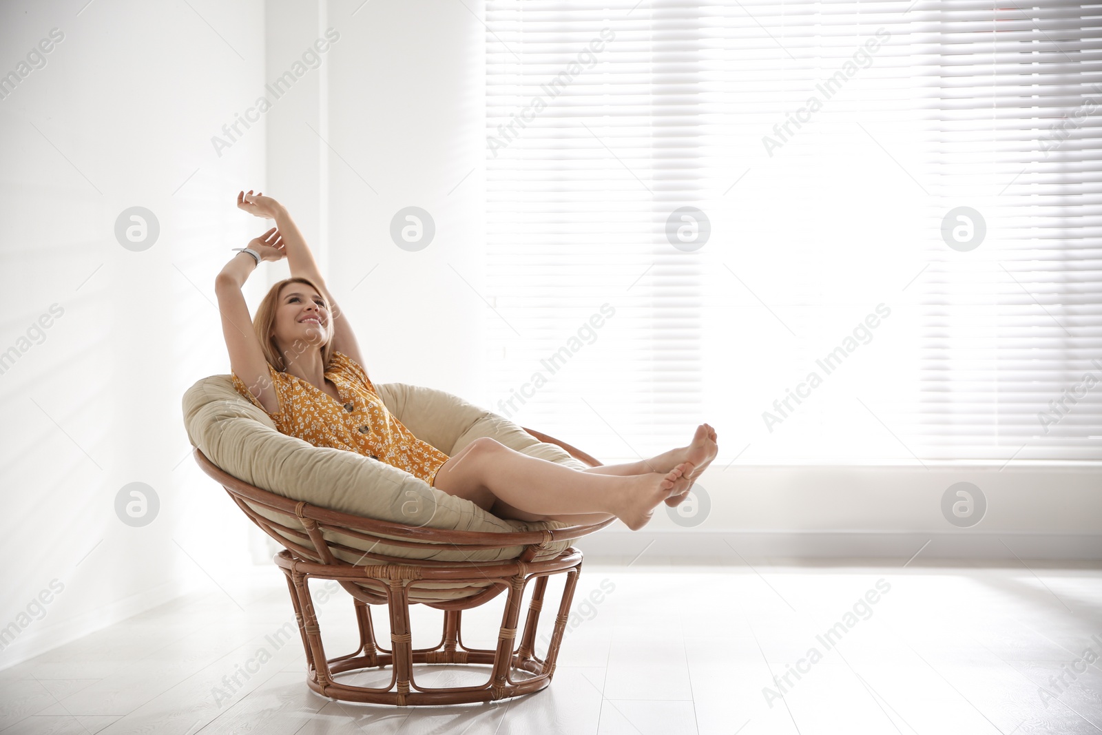 Photo of Young woman relaxing in papasan chair near window at home. Space for text