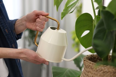 Photo of Woman watering beautiful potted houseplant indoors, closeup