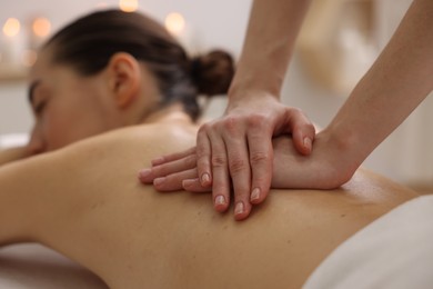 Photo of Woman receiving back massage in spa salon, focus on hands