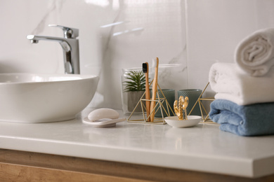 Toiletries and stylish vessel sink on light countertop in modern bathroom