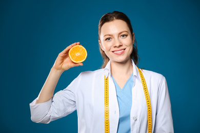 Photo of Nutritionist with ripe orange on blue background