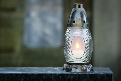 Photo of Grave lantern with burning candle on tombstone in cemetery, space for text