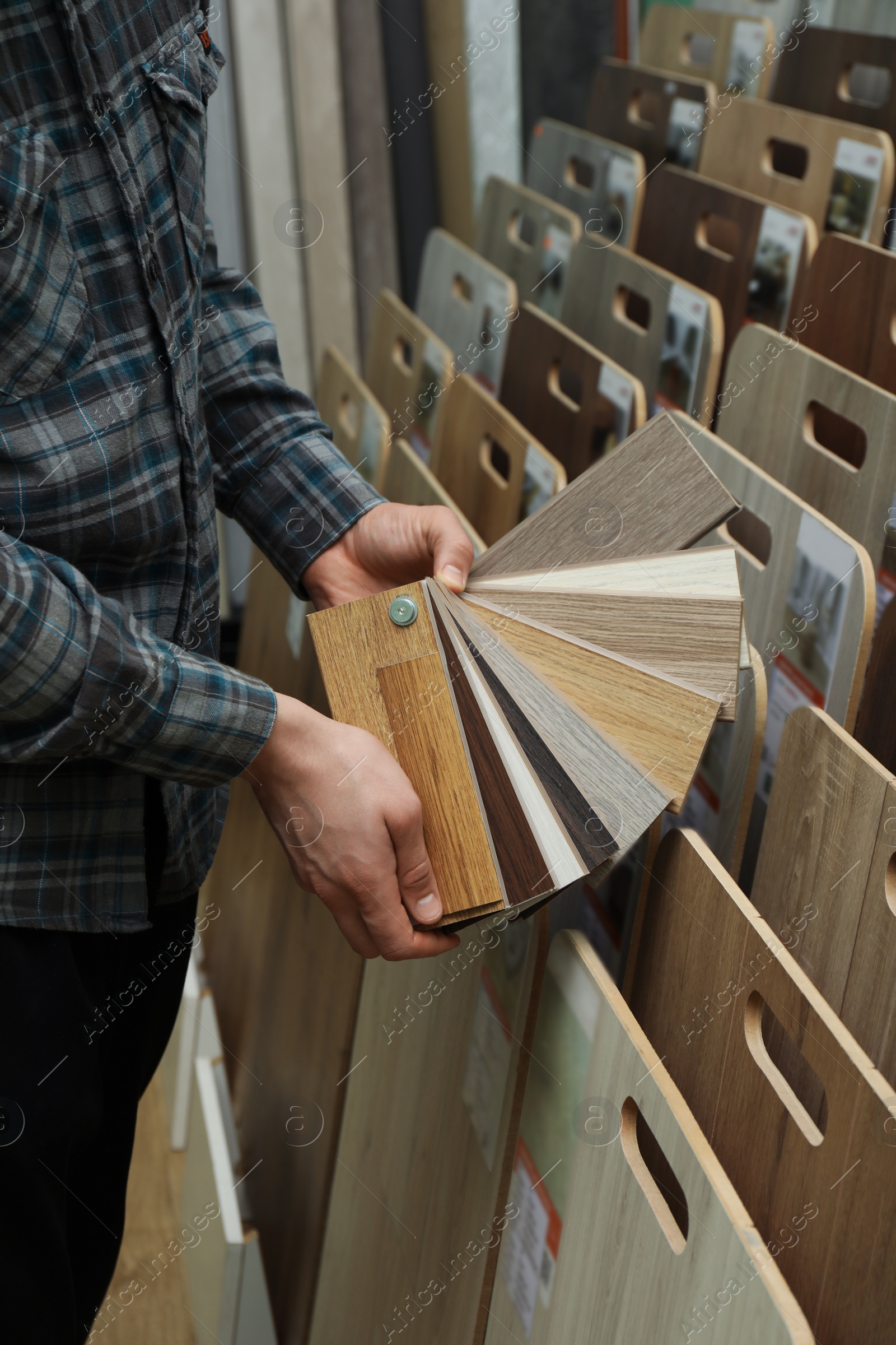 Photo of Man with samples of wooden flooring in shop, closeup