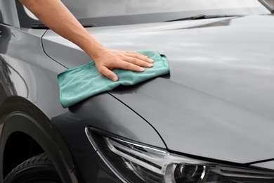 Photo of Man washing car hood with rag, closeup