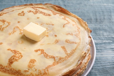 Photo of Plate with thin pancakes and butter on wooden table