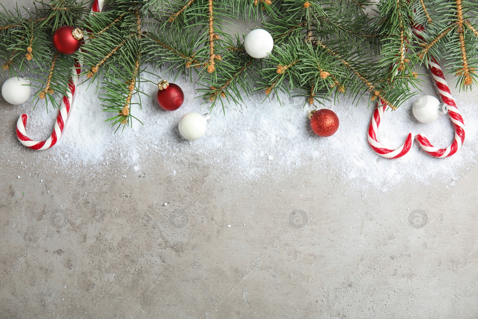 Photo of Flat lay composition with Christmas decor, snow and space for text on gray background. Festive winter design