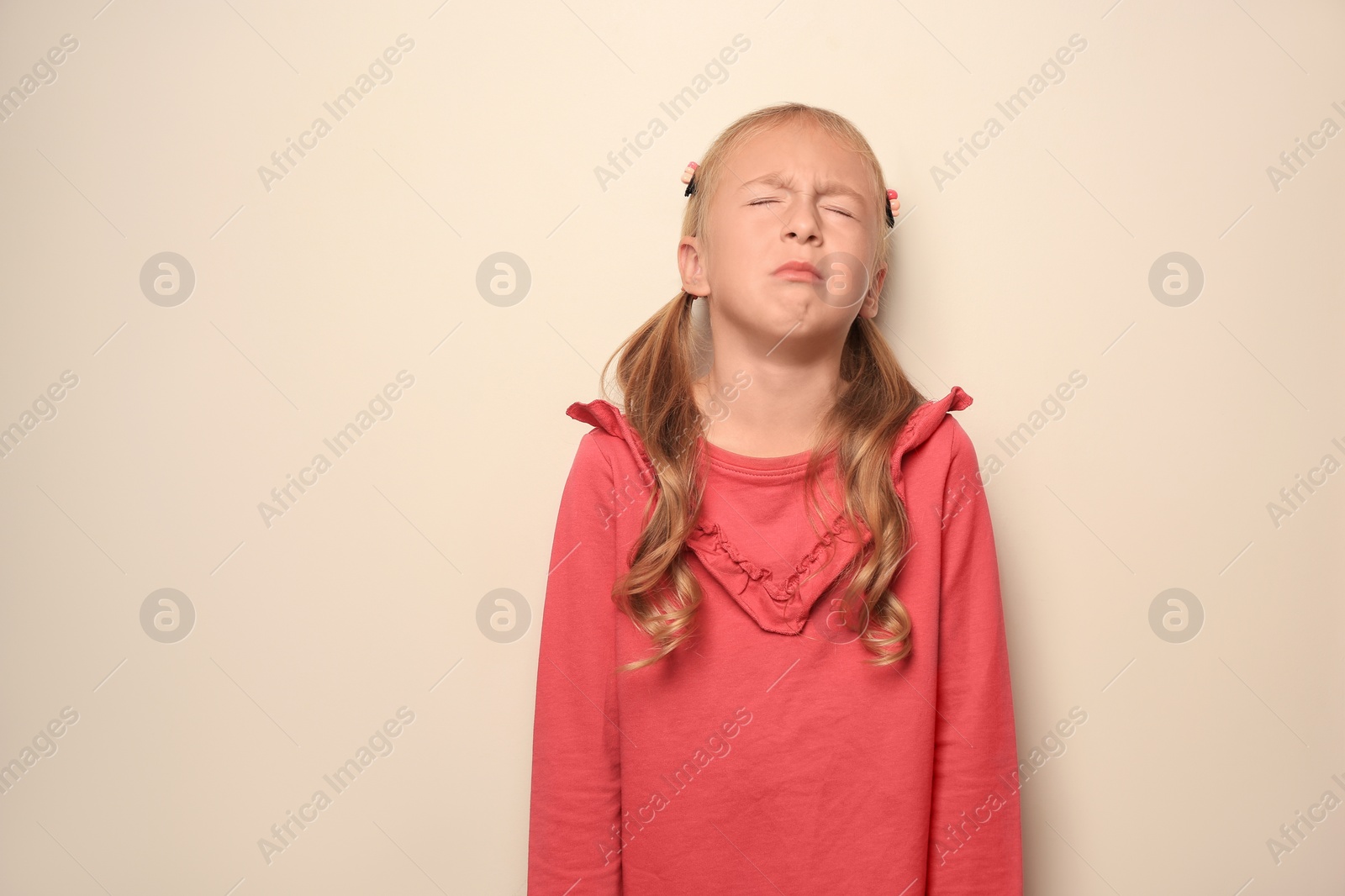 Photo of Cute little girl crying on light background. Space for text