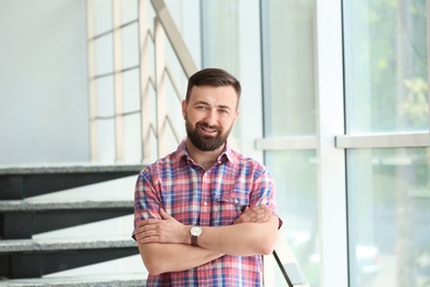 Portrait of handsome bearded man near stairs, indoors