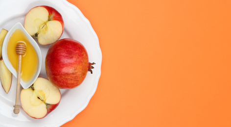 Photo of Honey, apples and pomegranate on orange background, top view. with space for text Rosh Hashanah holiday