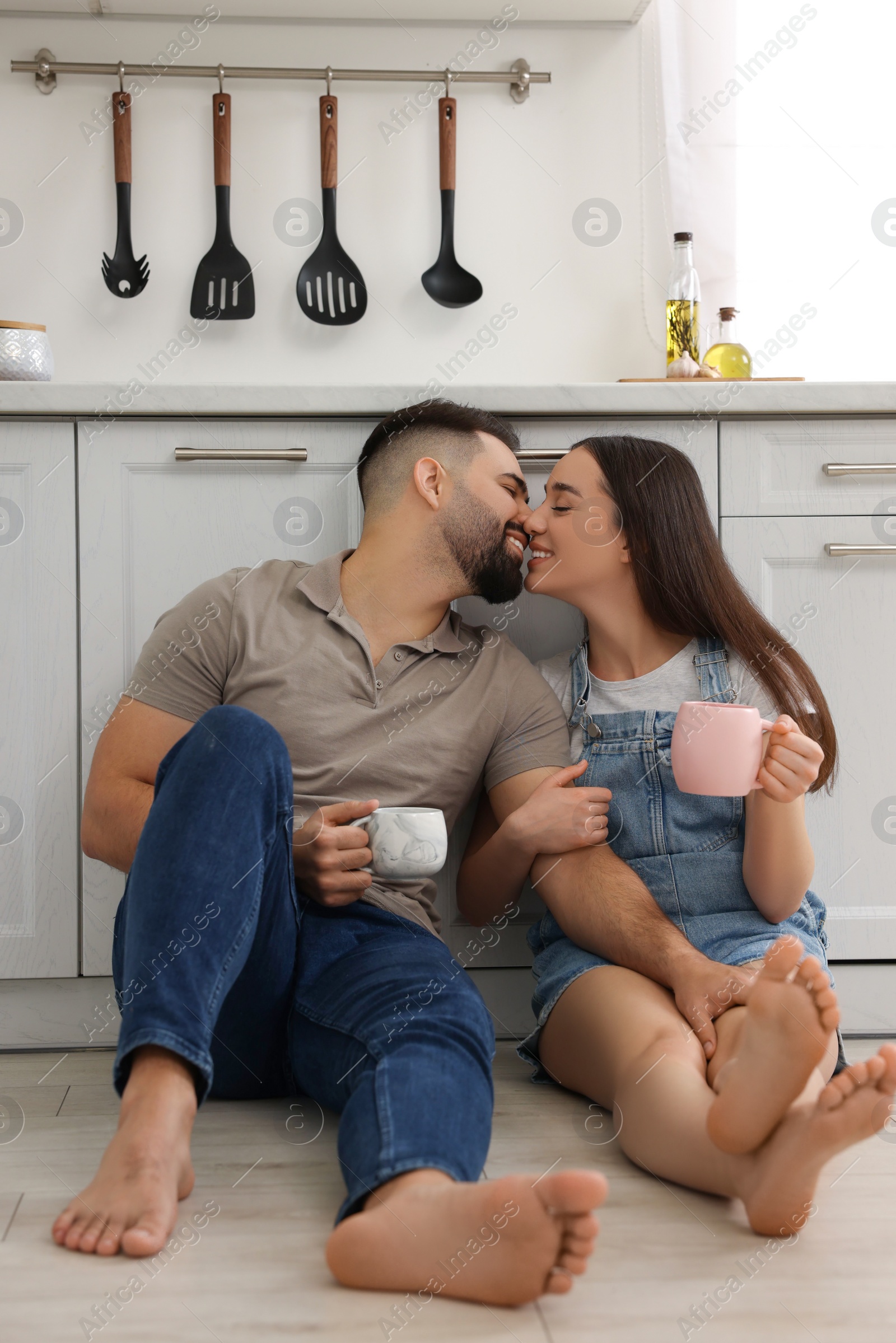 Photo of Affectionate young couple kissing in light kitchen