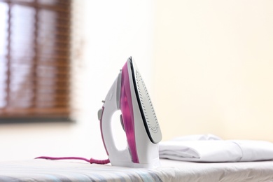 Photo of Modern iron and shirt on board in room