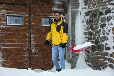 Man cleaning snow with shovel near his house