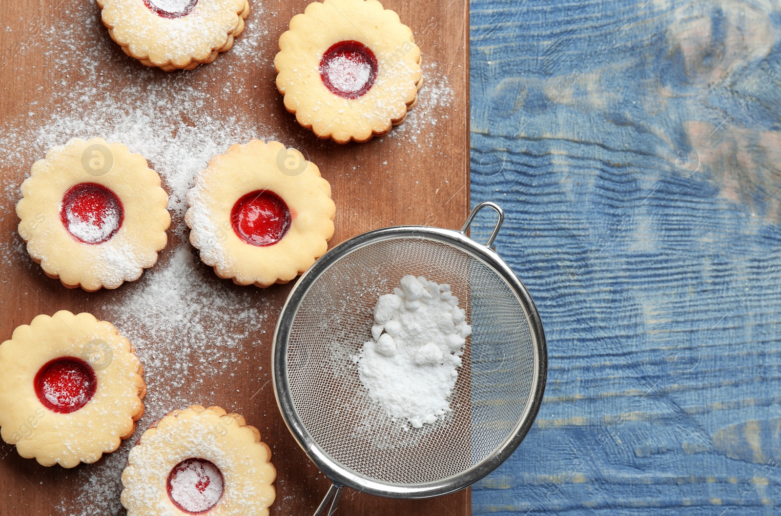 Photo of Traditional Christmas Linzer cookies with sweet jam and sugar powder on wooden background, top view