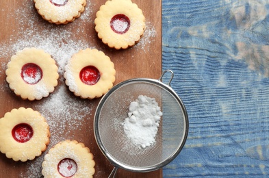 Photo of Traditional Christmas Linzer cookies with sweet jam and sugar powder on wooden background, top view