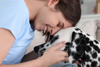 Photo of Beautiful woman with her adorable Dalmatian dog indoors, closeup. Lovely pet