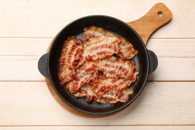 Photo of Delicious bacon slices in frying pan on white wooden table, top view