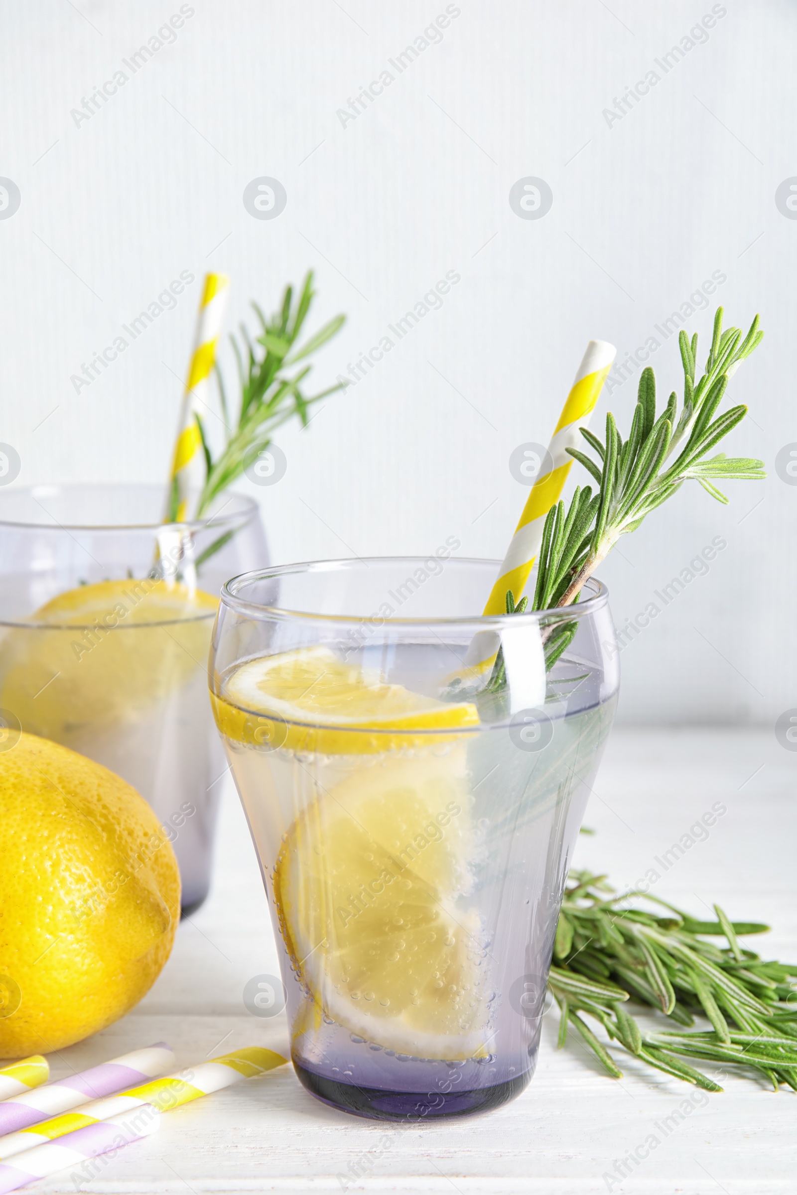 Photo of Tasty refreshing lemon cocktail with rosemary on table