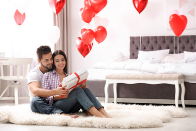 Photo of Happy young couple in bedroom decorated with heart shaped balloons. Valentine's day celebration