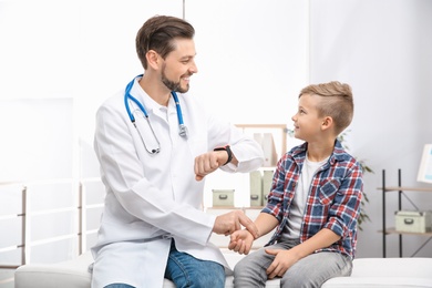 Doctor checking little boy's pulse with fingers in hospital