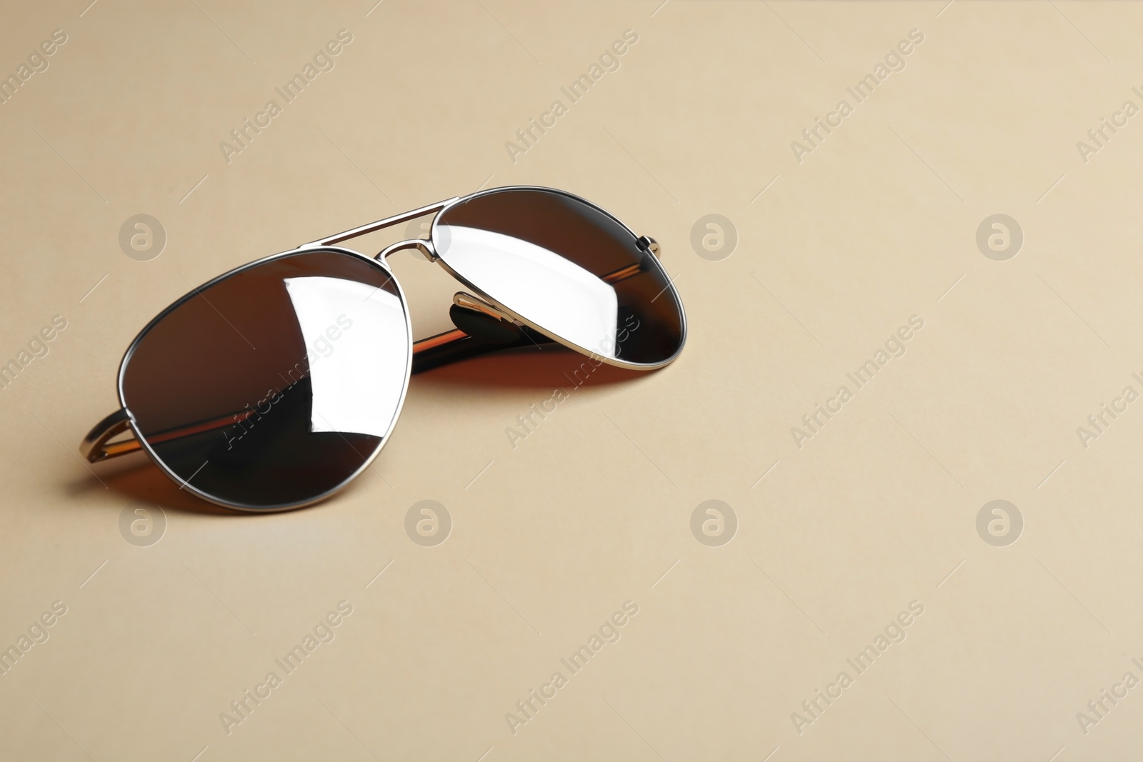 Photo of Stylish sunglasses on beige background, space for text. Fashionable accessory