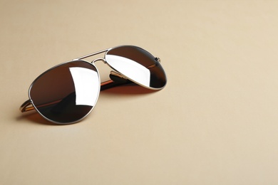 Photo of Stylish sunglasses on beige background, space for text. Fashionable accessory