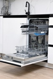 Photo of Open clean empty dishwasher in kitchen. Home appliance