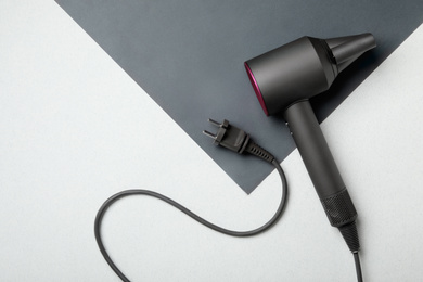 Photo of Hair dryer on color background, top view. Professional hairdresser tool