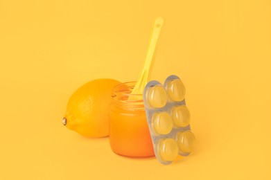 Blister with cough drops, fresh lemon and honey on orange background