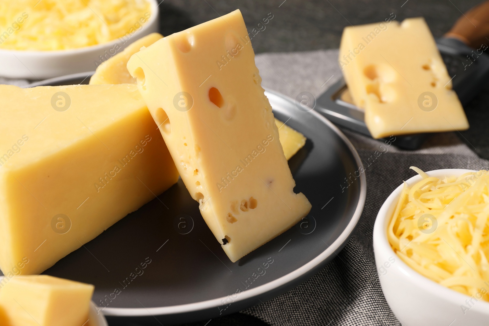 Photo of Grated and whole pieces of cheese on table, closeup