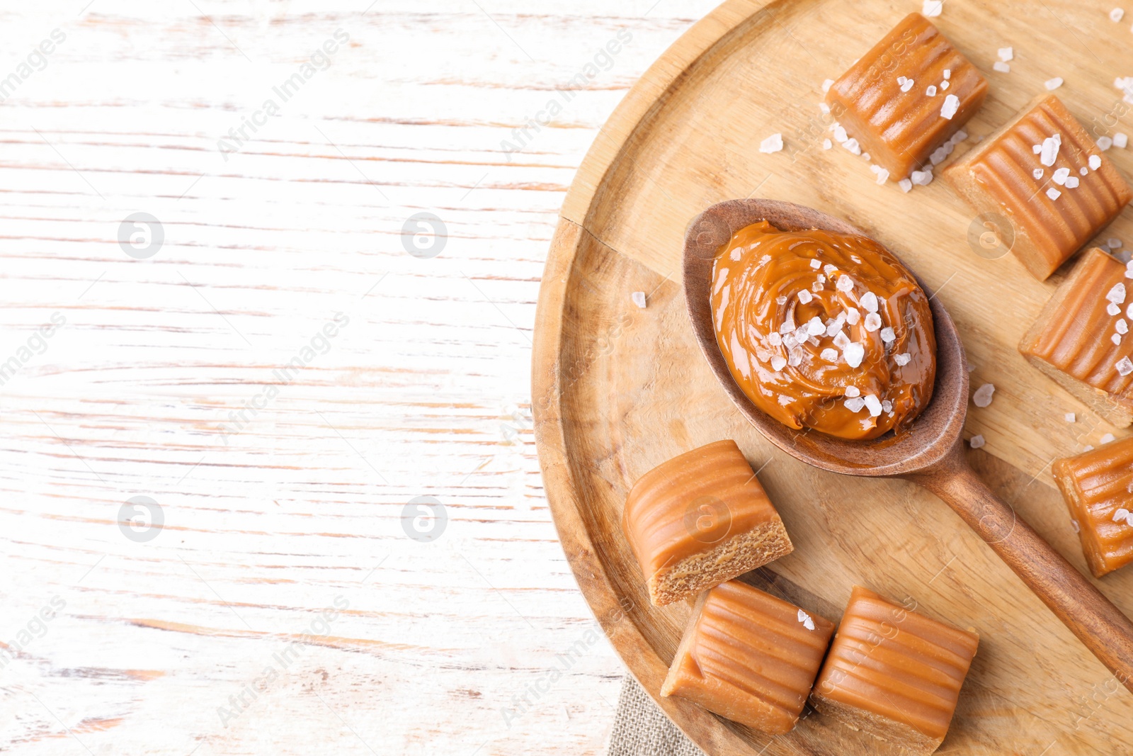 Photo of Salted caramel on white wooden table, top view. Space for text