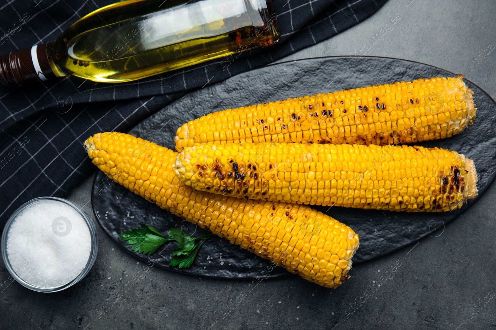 Photo of Fresh grilled corn cobs on grey table, flat lay