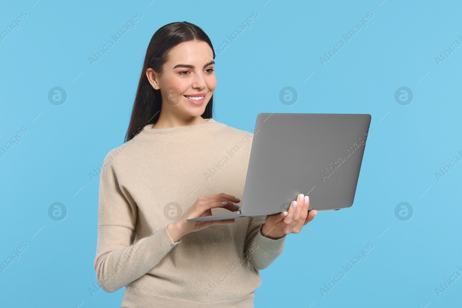 Photo of Happy woman using laptop on light blue background