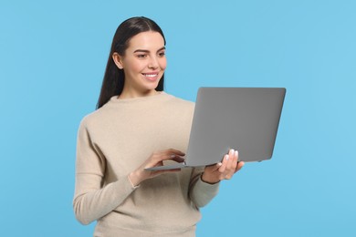 Happy woman using laptop on light blue background