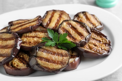 Photo of Delicious grilled eggplant slices on plate, closeup