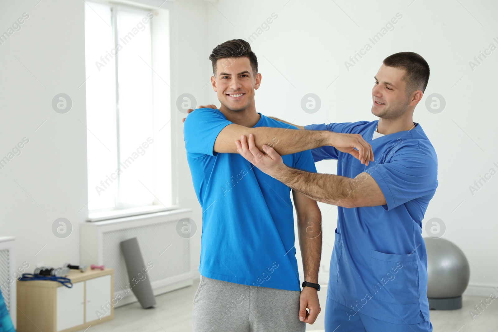 Photo of Professional physiotherapist working with male patient in rehabilitation center