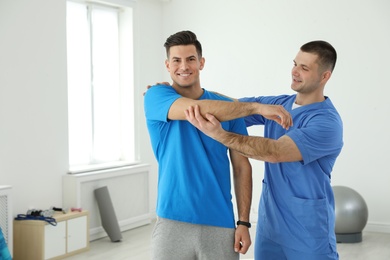 Professional physiotherapist working with male patient in rehabilitation center