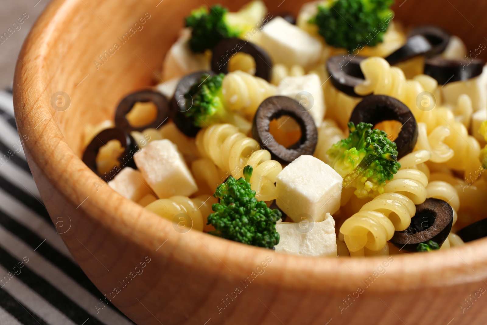 Photo of Wooden bowl with delicious pasta primavera, closeup