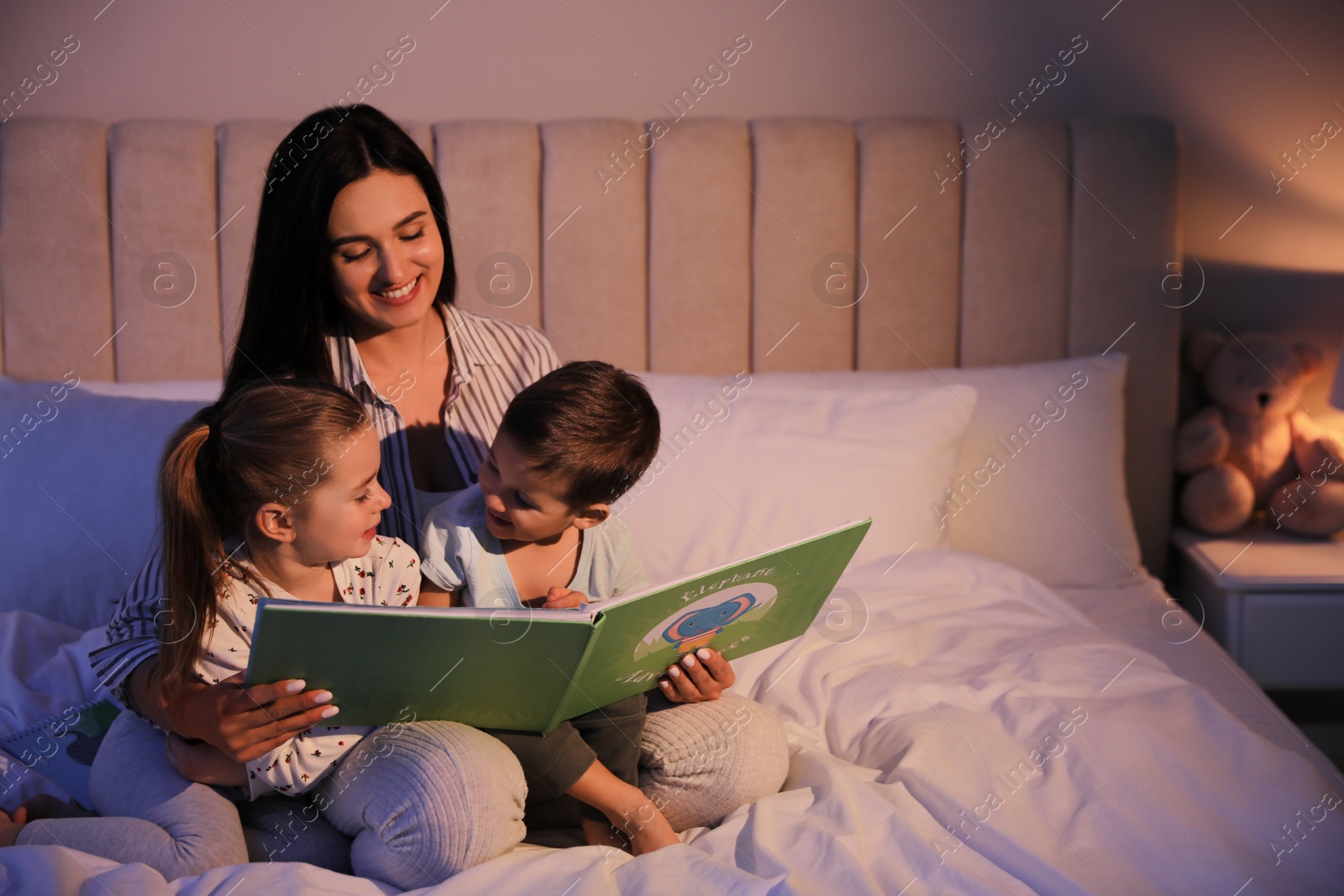 Photo of Mother reading bedtime story to her children at home