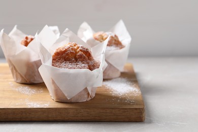 Photo of Delicious muffins with powdered sugar on light table, closeup