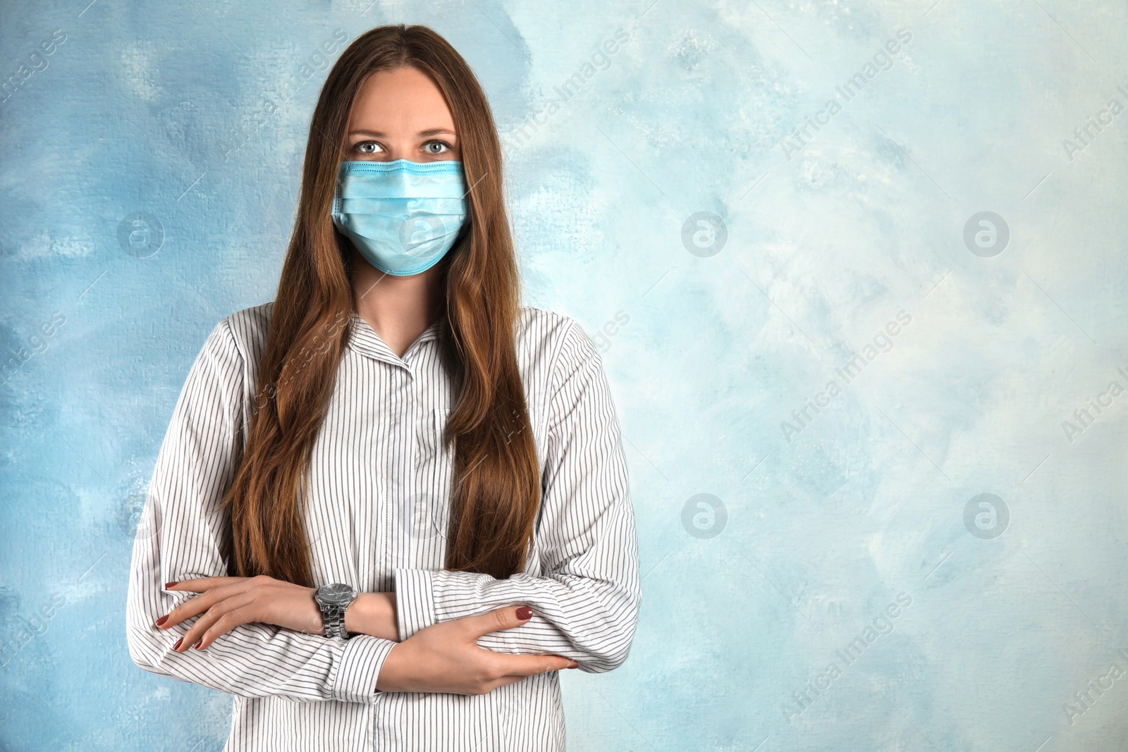 Photo of Woman with disposable mask on face against light blue background. Space for text