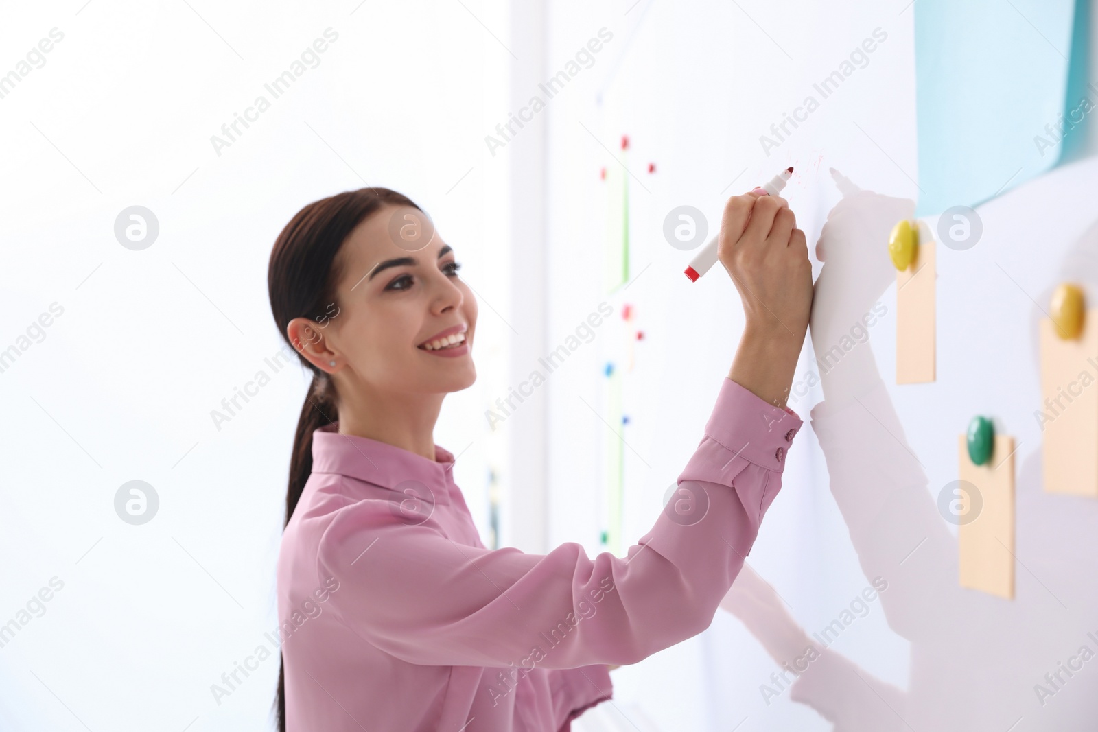 Photo of Young teacher writing on whiteboard in classroom