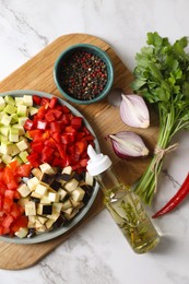 Cooking delicious ratatouille. Fresh ripe vegetables and plate on white marble table, flat lay