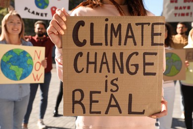 Woman with poster protesting against climate change outdoors, closeup