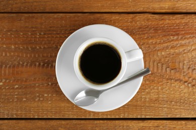 Photo of Cup of tasty coffee on wooden table, top view