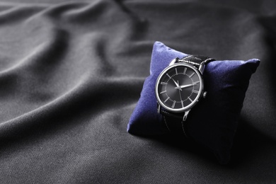Photo of Small decorative pillow with luxury wrist watch on black background. Fashion accessory