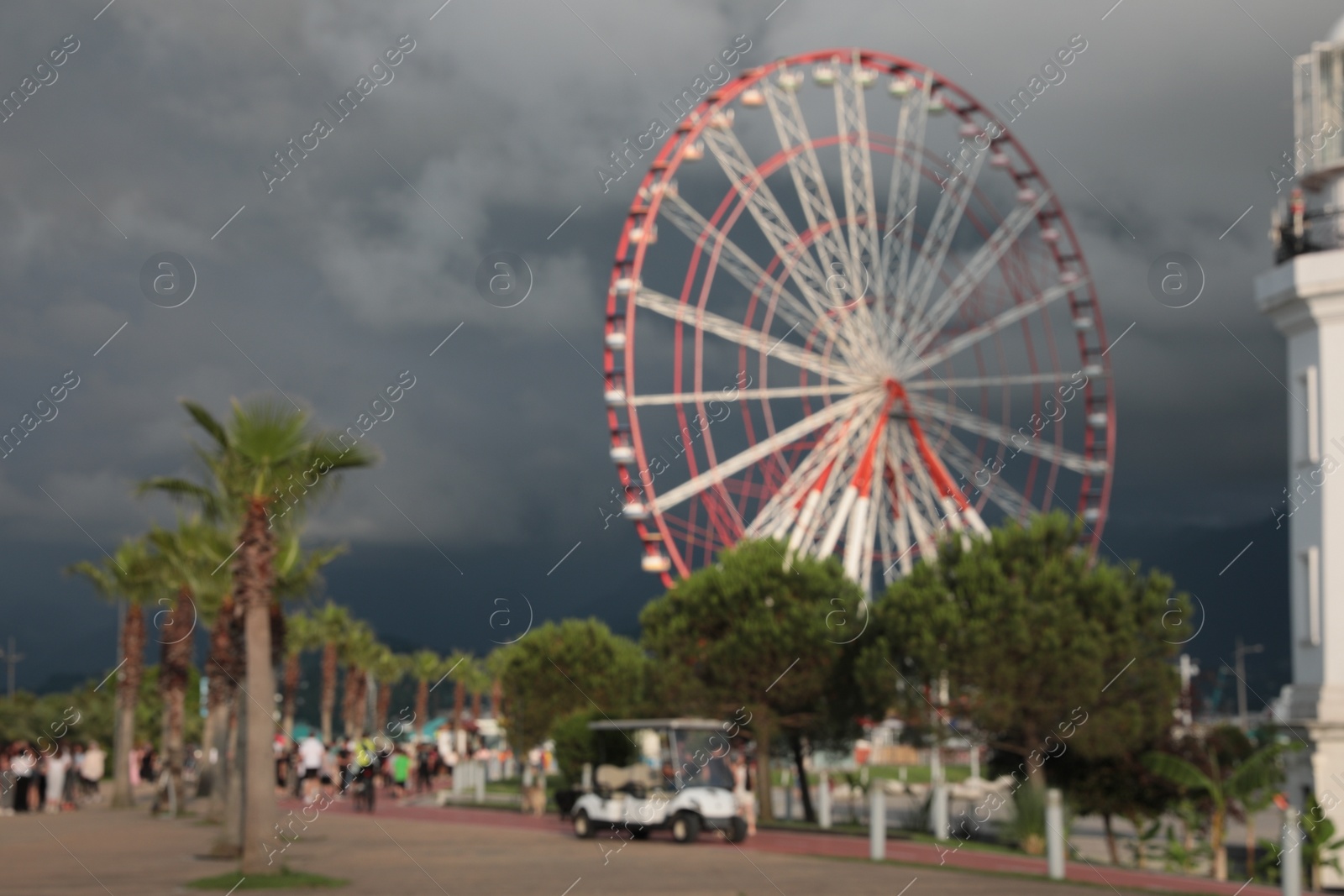 Photo of Blurred view of large Ferris wheel in park under rainy clouds