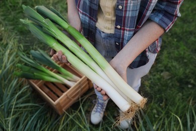 Woman holding fresh raw leeks outdoors, above view