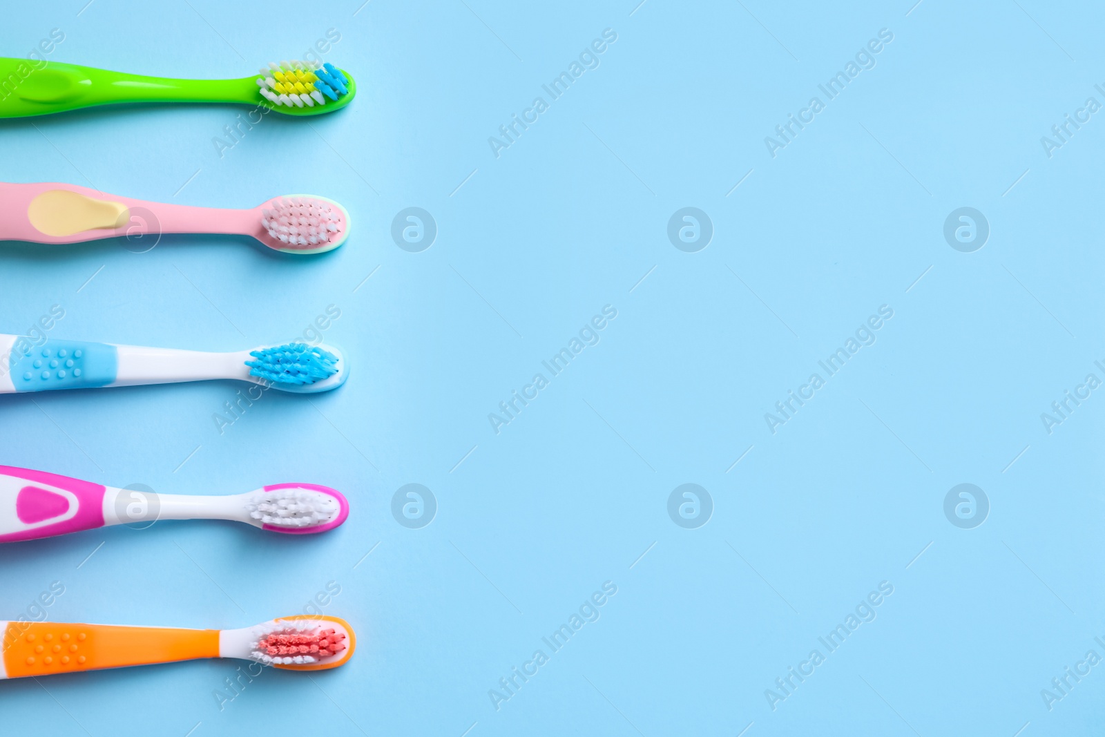 Photo of Different toothbrushes and space for text on light blue background, flat lay