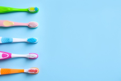 Photo of Different toothbrushes and space for text on light blue background, flat lay