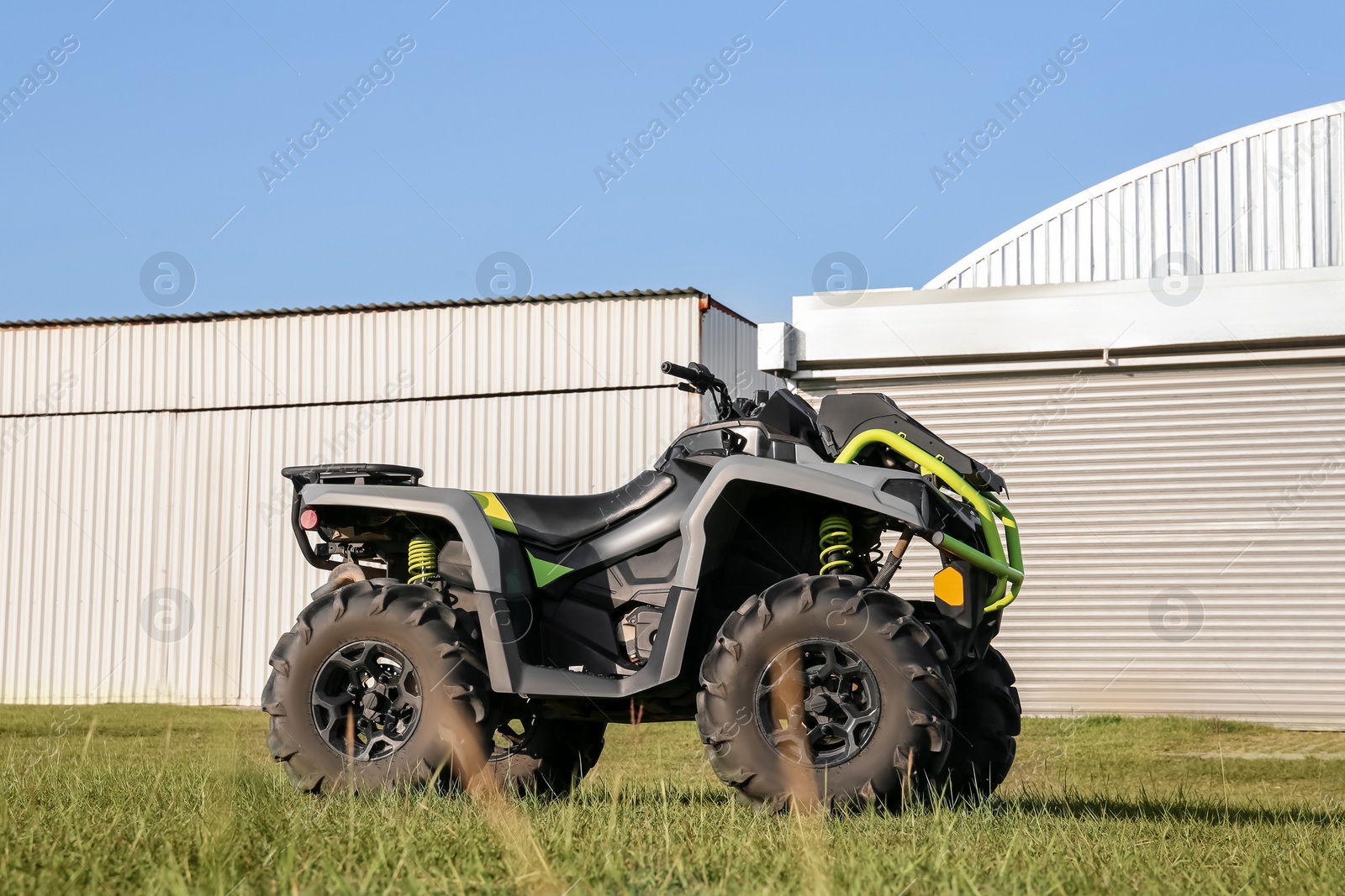 Photo of Modern quad bike in field near hangars on sunny day